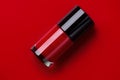 Red nail polish bottle over bright red background, top view. Gel nailpolish, shellac UV, bottle with brush