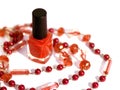 Red nail polish bottle surrounded by necklace