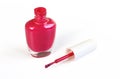 Red nail polish on white background. Opened glass bottle