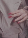 Red nails on the background of a beige coat, autumn photo