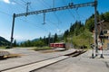 Red narrow gauge train arrives at a remote train station in the Swiss Alps Royalty Free Stock Photo
