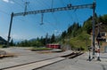 Red narrow gauge train arrives at a remote train station in the Swiss Alps Royalty Free Stock Photo