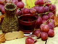 Red natural jucie homemade wicker bottle and grapes Royalty Free Stock Photo