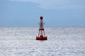 Red navigational buoy with light on top and small solar panels for charging surrounded with restless sea Royalty Free Stock Photo