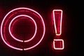 Red neon light letter and exclamation point on a black wall