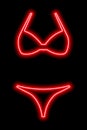 Red neon silhouette of a women's swimsuit on a black background. Bikini Royalty Free Stock Photo