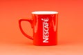 Red Nescafe mug isolate on red background.