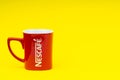 Red Nescafe mug isolate on yellow background