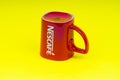 Red Nescafe mug isolate on yellow background