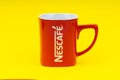 Red Nescafe mug isolate on yellow background