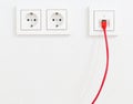 Red network cable in wall outlet for office or private home lan ethernet connection with power outlets flat view on white plaster Royalty Free Stock Photo