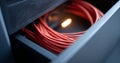 Close-up of red network cables coiled inside a dark server rack with soft lighting and metal mesh panel Royalty Free Stock Photo