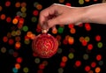 Red New Year`s ball with patterns in hand, on dark background