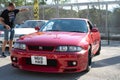 red ninth-generation Nissan Skyline GT-R33 at a Japanese sports car meet.