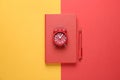 Red notebook, alarm clock and pen on background, top view