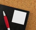 Red notebook and black glases on the cork board