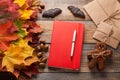 Red notebook and cookies for Halloween in the form of bats and gingerbread men-vampires on the old wooden table. Mixed maple autum