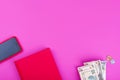 Red notebook for records, phone in red case, money of different currencies on a pink background Royalty Free Stock Photo