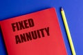 Red notebook with text fixed annuity and yellow pencil on vibrant blue background Royalty Free Stock Photo