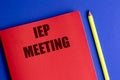 Red notebook with text IEP meeting and yellow pencil on blue background Royalty Free Stock Photo