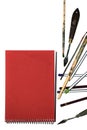 Red notepad and colored paints on a white background