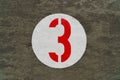 Red number three inside white circle painted on concrete Royalty Free Stock Photo