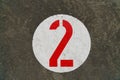 Red number two inside white circle painted on concrete Royalty Free Stock Photo