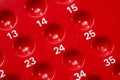 Red numbered bingo game board close-up detail, empty slots holes for bingo or lottery, random number sequence concept, row, game