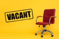 Red office chair and word VACANT on yellow background