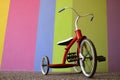 Red Old Childrens Bike in front of a Bright Colored Wall