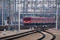 The red old electric train arrives at the station of the railway station Track, poles and supports for current-carrying lines Royalty Free Stock Photo