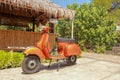 Red old-fashioned scooter motorbike - indonesian traditional way of transportation on a tropical island. Orange vintage vespa. Royalty Free Stock Photo