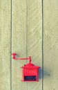 Red old mechanical coffee grinder on white wooden table.