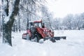 A red old tractor clears the street of snow in a snow storm. Street cleaning in winter Royalty Free Stock Photo