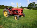 Red old tractor standing in a green field