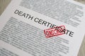 Red omicron seal standing on death certificate document closeup