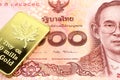 A red one hundred Thai baht note with a gold bar in macro Royalty Free Stock Photo