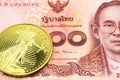 A red one hundred Thai baht note with a gold coin in macro Royalty Free Stock Photo