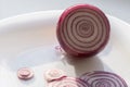 Red onion and slices rings on white plate. Raw juicy vegetable