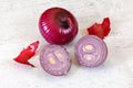 Red onion on white stone desk, whole one with some skin peeled in background, and halved ball at foreground Royalty Free Stock Photo