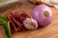 Red onions, garlic, peppers, and kaffir lime leaves on a wooden table Royalty Free Stock Photo