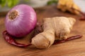 Red onions, peppers, and ginger on a wooden table Royalty Free Stock Photo