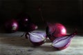 Red onions whole and halved on rustic dark wood Royalty Free Stock Photo