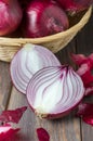 Red onions in a wicker basket. Fresh harvest. Brown wooden background Royalty Free Stock Photo