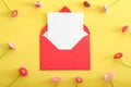 Red open envelope with blank paper card mockup and wildflowers on yellow background. Flat lay composition, top view, copy space. Royalty Free Stock Photo