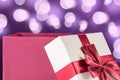 Magical Surprise: Red Gift Box with Bow on Purple Bokeh Background Royalty Free Stock Photo