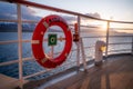 Red orange AIDA Bella lifebuoy attached to the cruise ship railing, sunset above Iceland snow mountain range in the background, Royalty Free Stock Photo