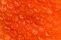 Red red-orange bubble wrap texture. Plastic for packaging fragile items. Air film abstract background. Close up, top view