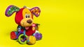 Red orange doggy toy on a yellow background with room for text. Soft plush toy for baby dog banner for toy store.