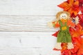 Red and orange fall leaves with a scarecrow on weathered whitewash wood textured background